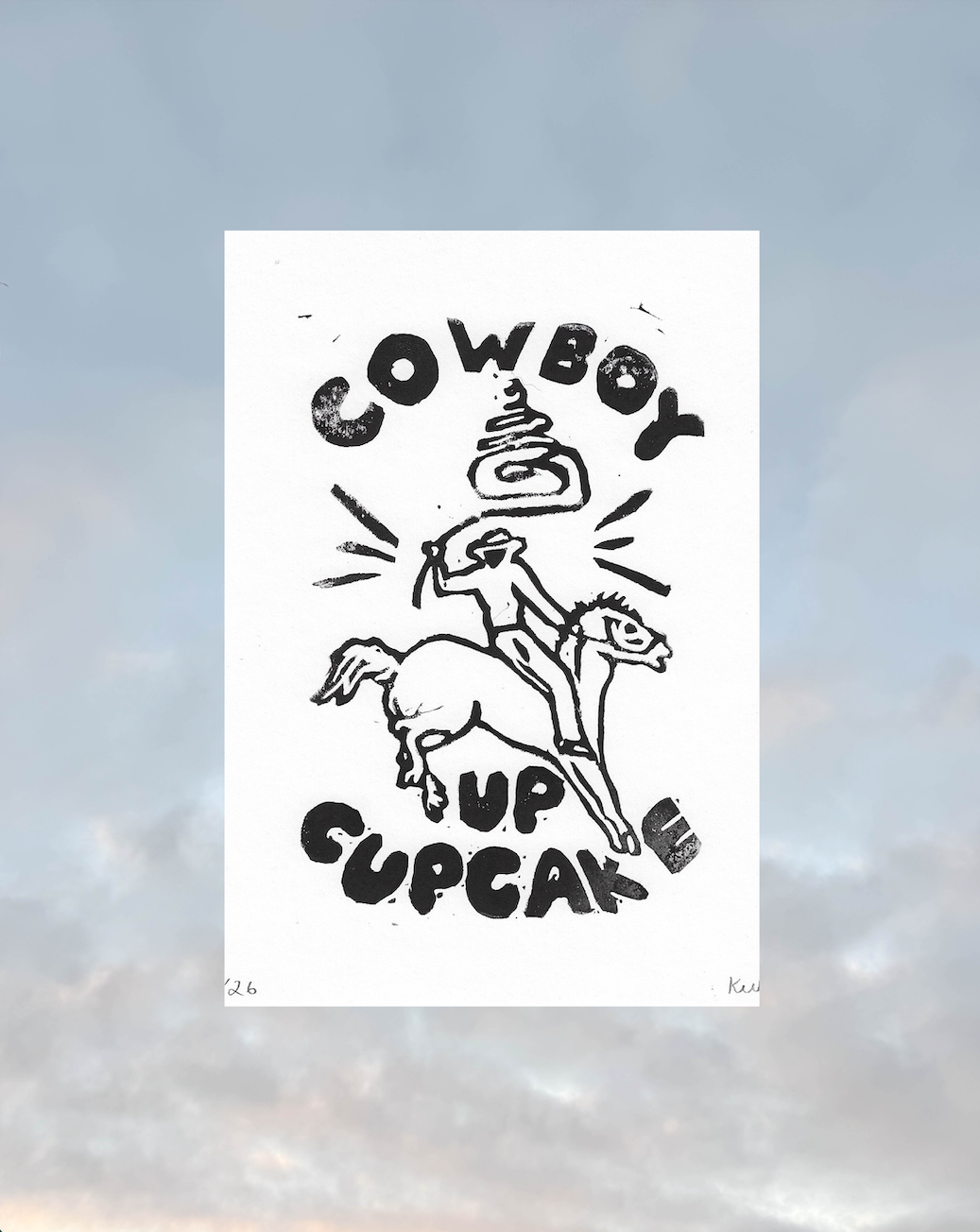 A black and white graphic print featuring a hand-drawn cowboy riding a horse with a cupcake on his head, surrounded by the text 'COWBOY UP CUPCAKE'. The print is displayed against a soft-focus sky background.